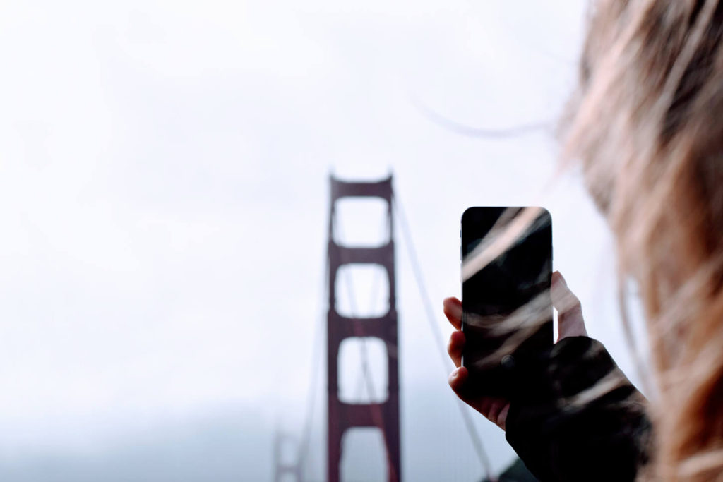 A woman taking picture of the Golden Gate Bridge.